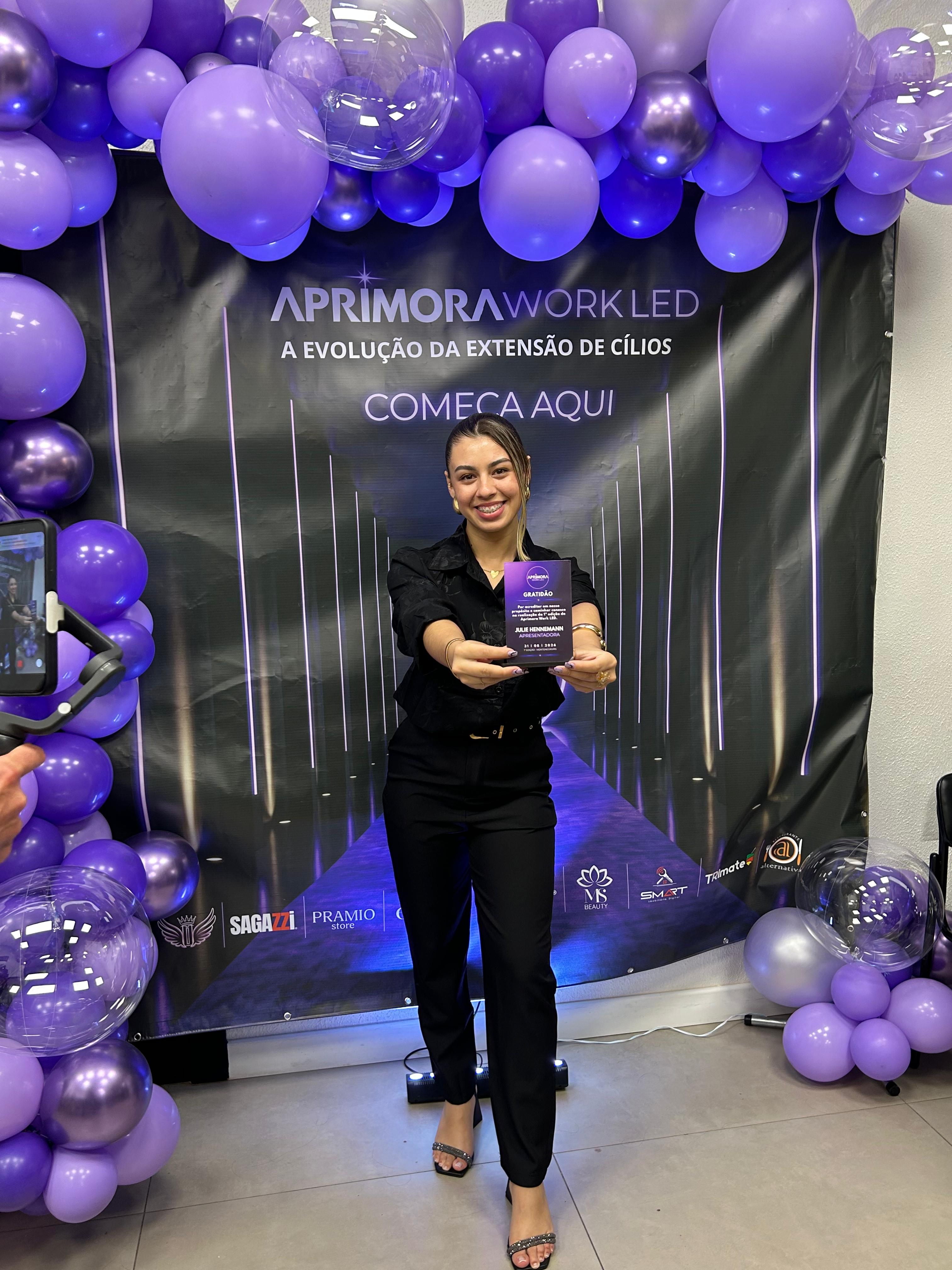 Julie Hennemann recebendo placa de gratidão como apresentadora da 1ª edição do Aprimora Work LED